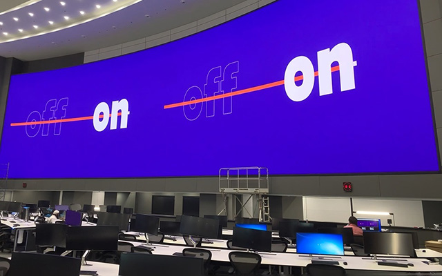 A huge curved LED videowall behind control room operators desks