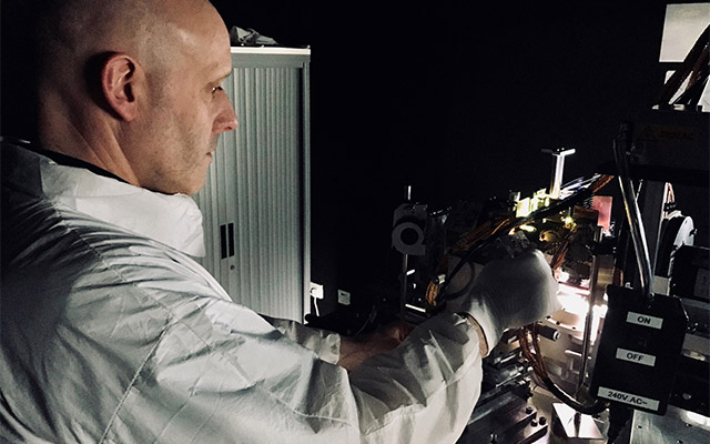 A man in a white coat adjusts projection equipment