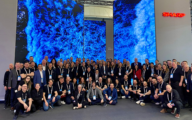 A group of people gather in front of a large LED screen